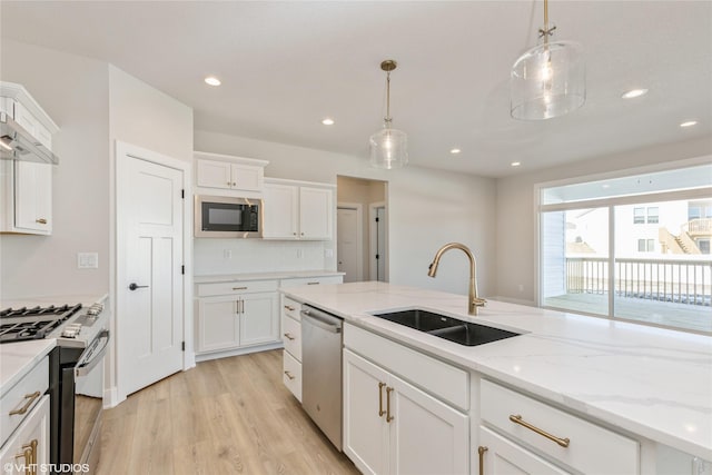 kitchen with appliances with stainless steel finishes, white cabinets, decorative light fixtures, and sink