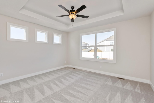 carpeted spare room featuring ceiling fan and a tray ceiling