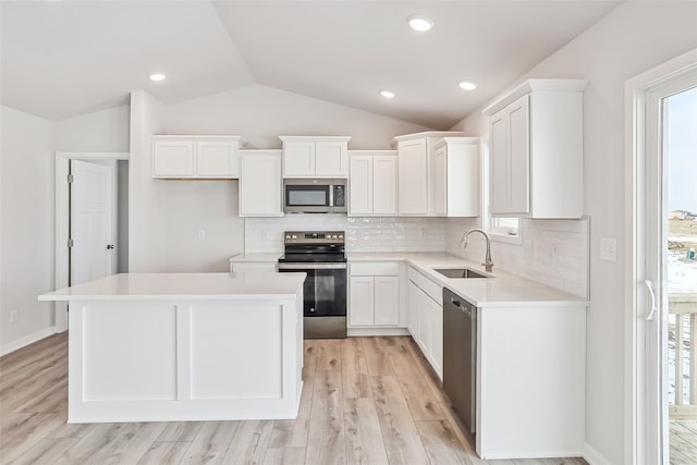 kitchen with a kitchen island, stainless steel appliances, white cabinets, and sink