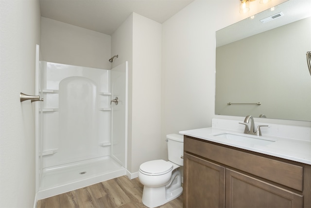 bathroom with hardwood / wood-style floors, walk in shower, vanity, and toilet