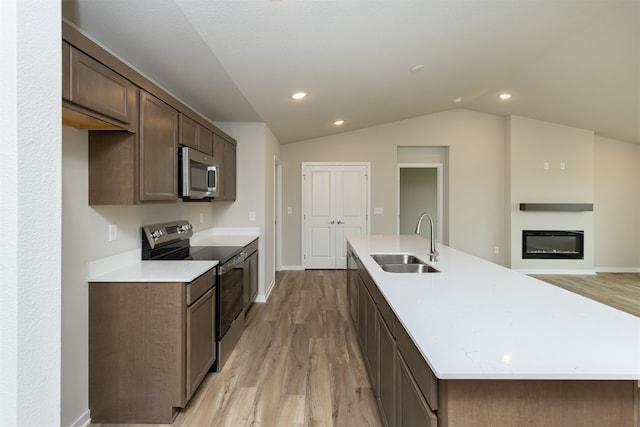 kitchen featuring appliances with stainless steel finishes, sink, an island with sink, and light hardwood / wood-style flooring