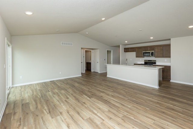 unfurnished living room featuring light hardwood / wood-style floors, sink, and vaulted ceiling