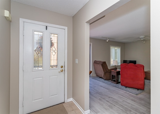 entrance foyer featuring ceiling fan, a textured ceiling, light wood-type flooring, and a wealth of natural light