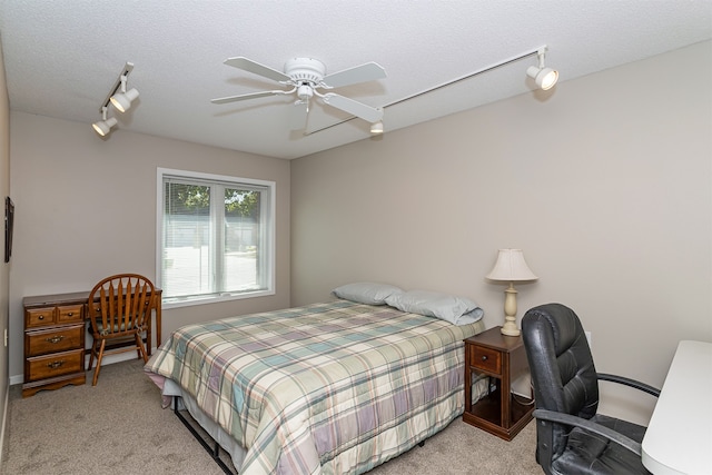 carpeted bedroom with ceiling fan, a textured ceiling, and track lighting