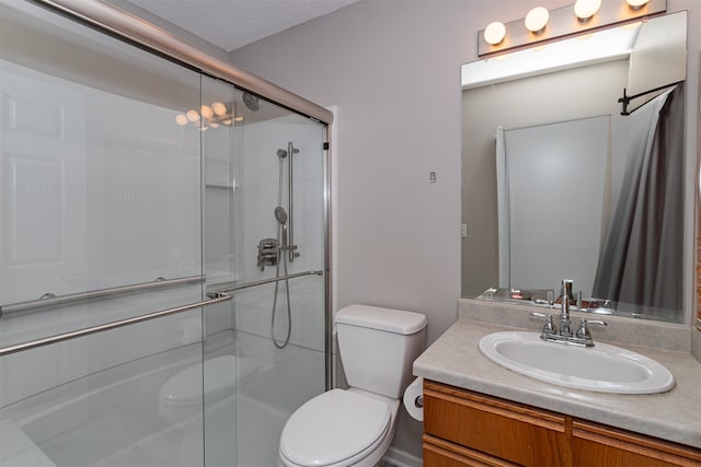 bathroom with a textured ceiling, vanity, toilet, and a shower with shower door