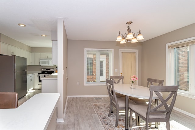 dining area with light hardwood / wood-style flooring and a chandelier