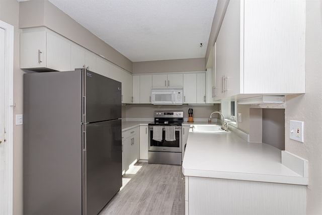 kitchen featuring a textured ceiling, sink, white cabinetry, light hardwood / wood-style flooring, and stainless steel appliances