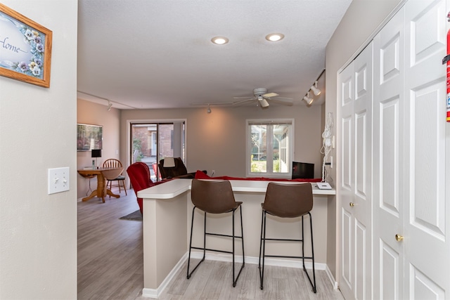 kitchen featuring a breakfast bar, light wood-type flooring, kitchen peninsula, and rail lighting