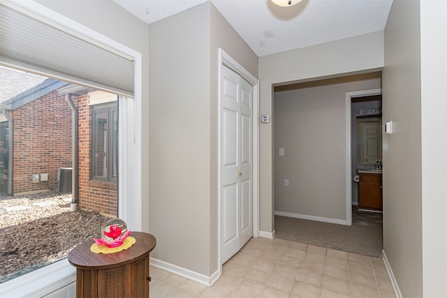 hallway with light carpet and a textured ceiling