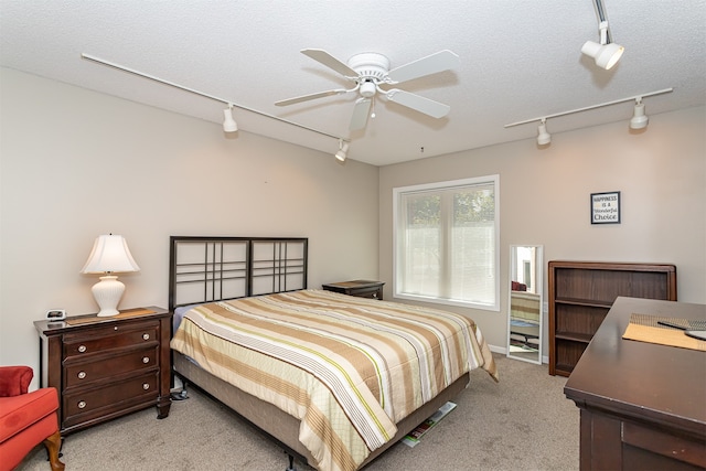 carpeted bedroom featuring ceiling fan, a textured ceiling, and rail lighting