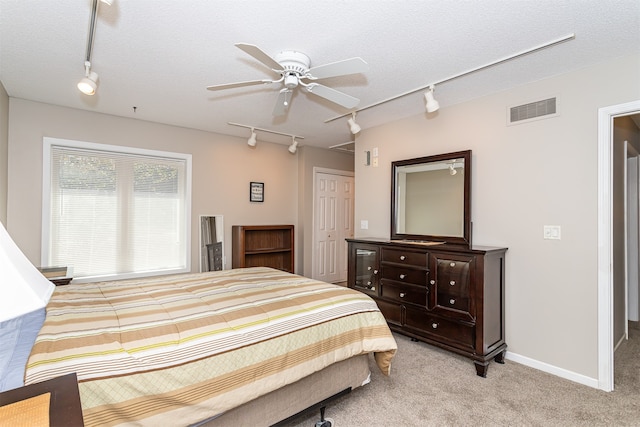 bedroom with a textured ceiling, ceiling fan, light carpet, and a closet