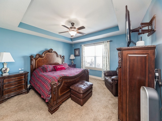 carpeted bedroom featuring a tray ceiling and ceiling fan