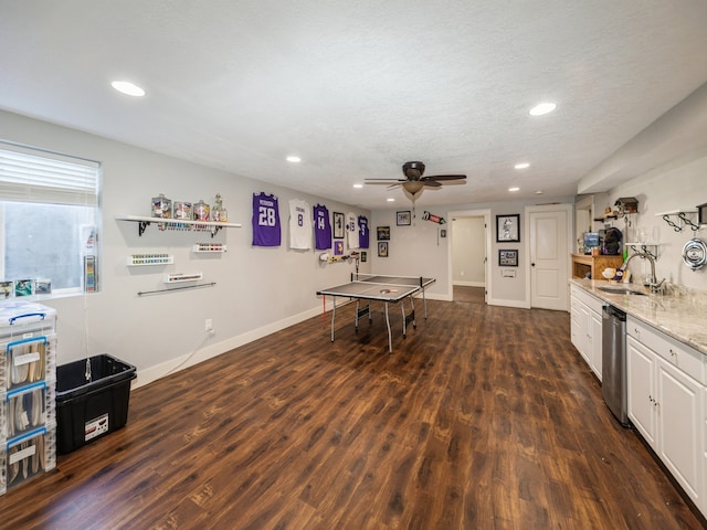 playroom with ceiling fan, sink, dark wood-type flooring, and a textured ceiling