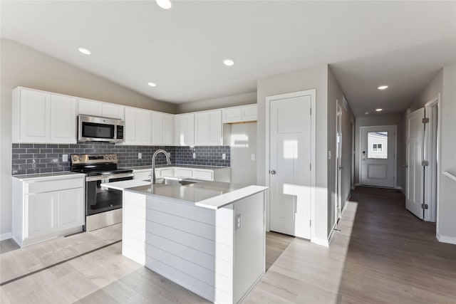 kitchen featuring lofted ceiling, sink, white cabinetry, an island with sink, and stainless steel appliances