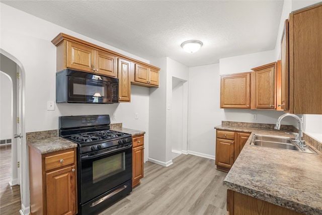 kitchen with black appliances, sink, a textured ceiling, and light hardwood / wood-style floors