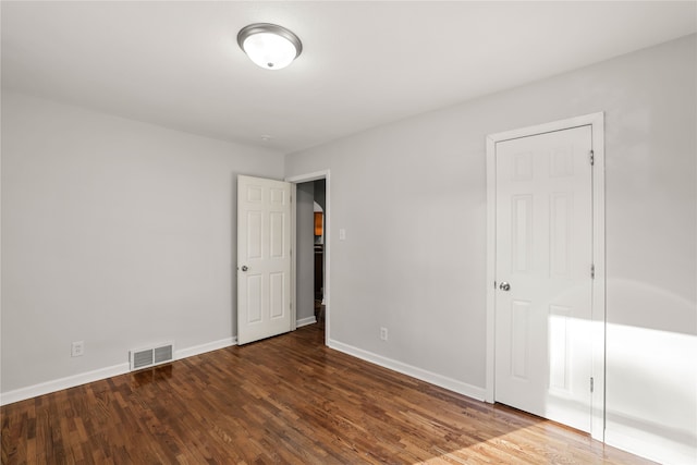 unfurnished bedroom featuring dark wood-type flooring and a closet