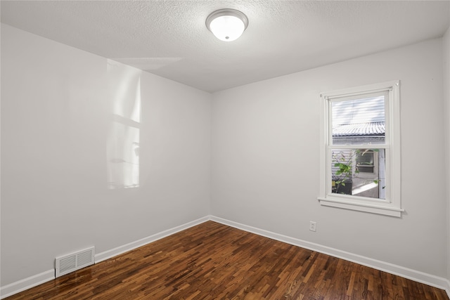 unfurnished room with a textured ceiling and dark hardwood / wood-style floors