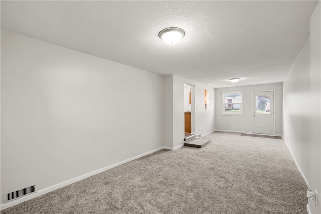 carpeted foyer entrance with a textured ceiling