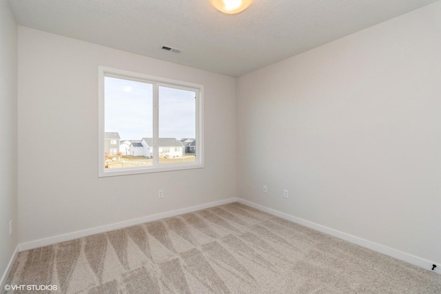 empty room with carpet flooring, baseboards, visible vents, and a textured ceiling