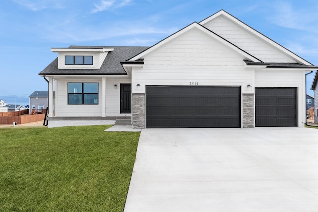 modern inspired farmhouse featuring a shingled roof, concrete driveway, an attached garage, a front yard, and stone siding