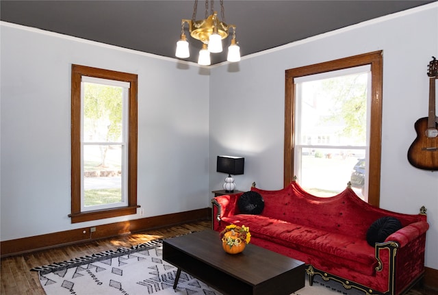 living room featuring ornamental molding, plenty of natural light, hardwood / wood-style floors, and a notable chandelier