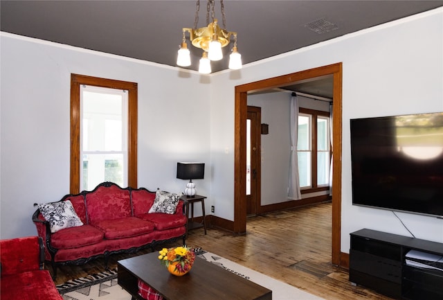 living room with ornamental molding, hardwood / wood-style flooring, and a notable chandelier