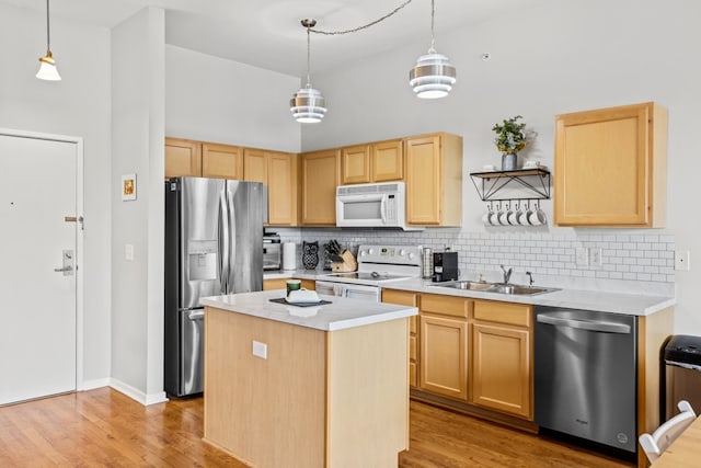 kitchen with sink, a kitchen island, stainless steel appliances, and decorative light fixtures