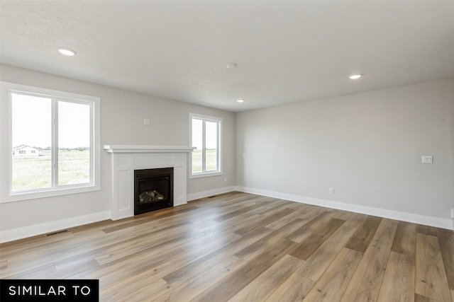 unfurnished living room featuring a textured ceiling and light hardwood / wood-style flooring