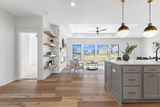 kitchen featuring pendant lighting, dark wood-type flooring, sink, gray cabinets, and a fireplace