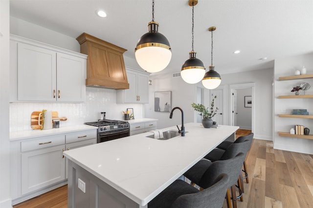 kitchen featuring pendant lighting, white cabinetry, sink, and a kitchen island with sink