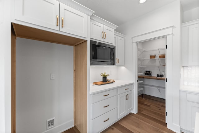 kitchen featuring white cabinetry, built in microwave, and light wood-type flooring