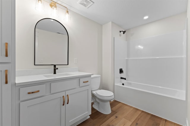 full bathroom with vanity, a textured ceiling, bathing tub / shower combination, hardwood / wood-style floors, and toilet