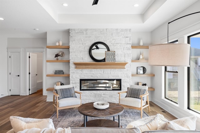 living room with a stone fireplace, plenty of natural light, and hardwood / wood-style flooring