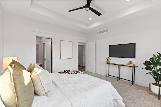 carpeted bedroom featuring a raised ceiling and ceiling fan