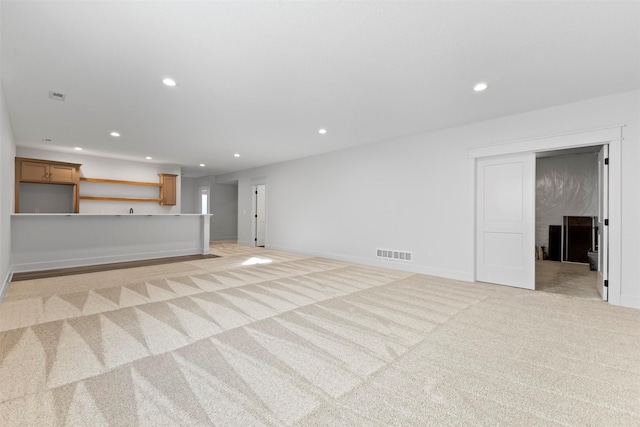 unfurnished living room with a high end fireplace and light colored carpet