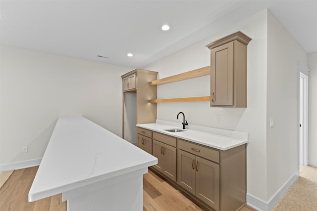 kitchen with light hardwood / wood-style floors, a kitchen island, light stone countertops, and sink