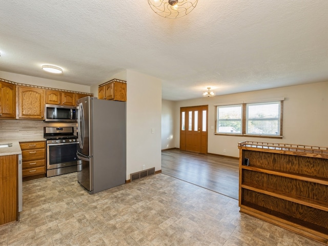 kitchen featuring a textured ceiling, appliances with stainless steel finishes, and light hardwood / wood-style floors