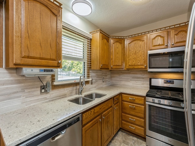 kitchen with light stone counters, sink, tasteful backsplash, a textured ceiling, and appliances with stainless steel finishes