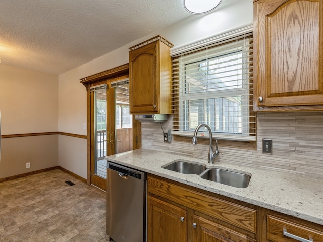 kitchen featuring sink, tasteful backsplash, a textured ceiling, dishwasher, and light stone countertops