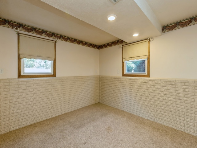 carpeted spare room featuring brick wall