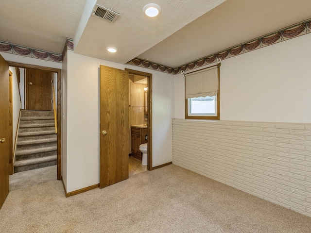 unfurnished bedroom featuring light carpet, connected bathroom, and a textured ceiling