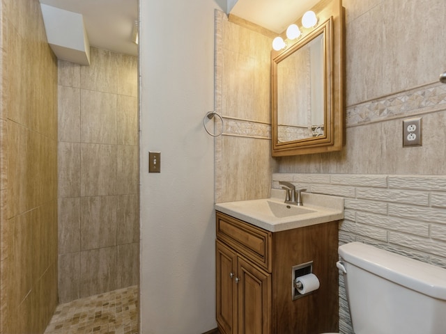 bathroom featuring tile walls, a tile shower, vanity, and toilet