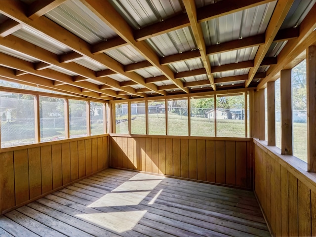 unfurnished sunroom featuring beamed ceiling and plenty of natural light