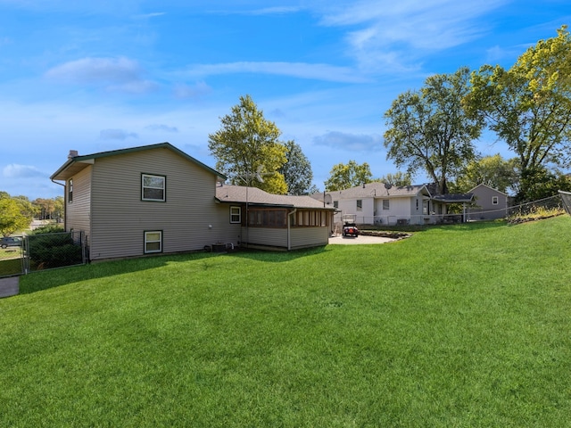 back of house featuring a sunroom and a lawn