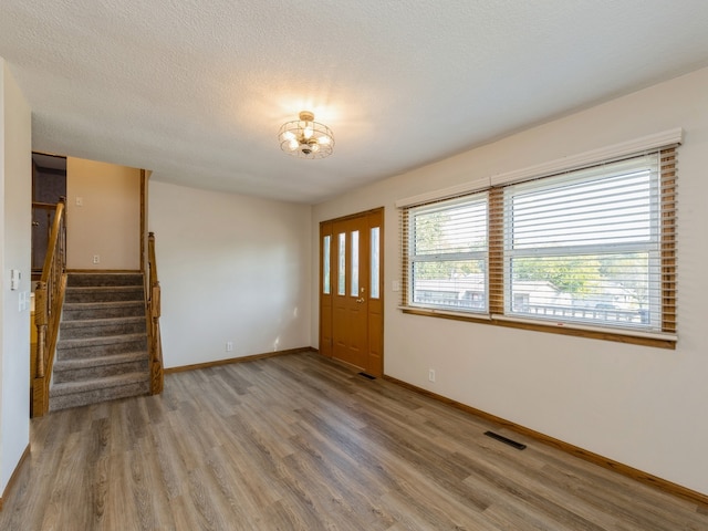 interior space with a textured ceiling and hardwood / wood-style floors