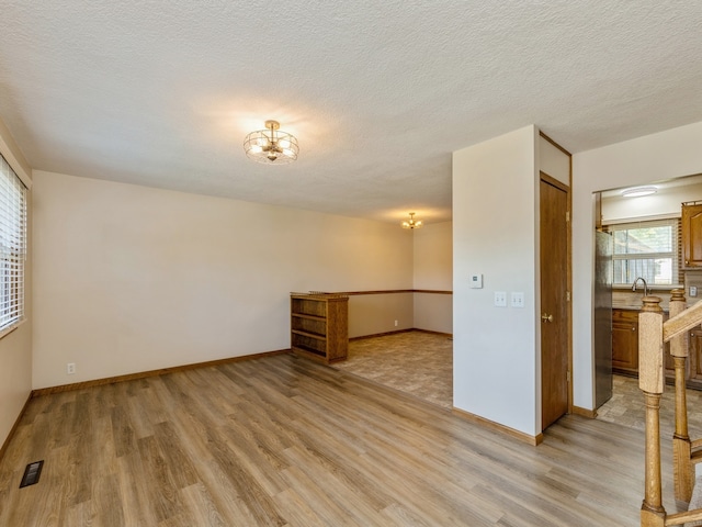 unfurnished room with light wood-type flooring and a textured ceiling