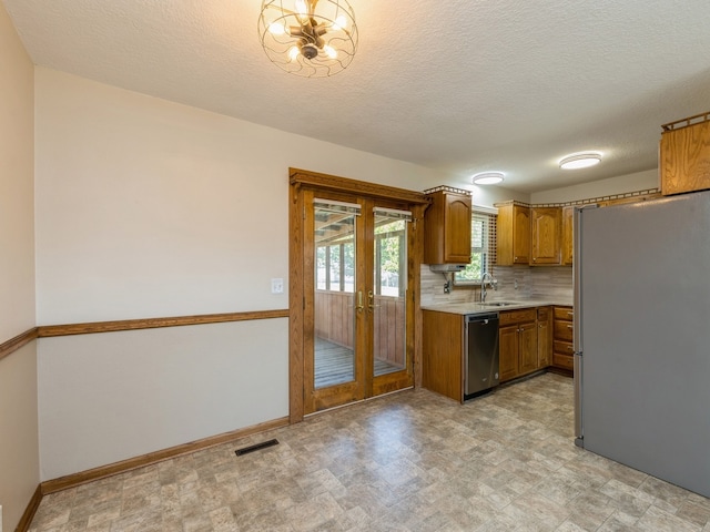 kitchen featuring sink, tasteful backsplash, french doors, a textured ceiling, and stainless steel appliances