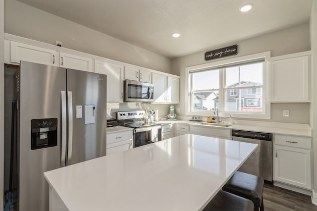 kitchen with stainless steel appliances, white cabinets, sink, and a center island