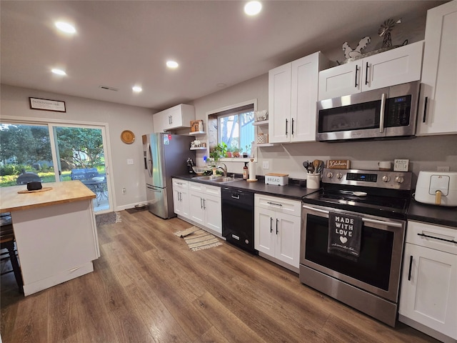 kitchen with white cabinetry, stainless steel appliances, wood finished floors, and recessed lighting