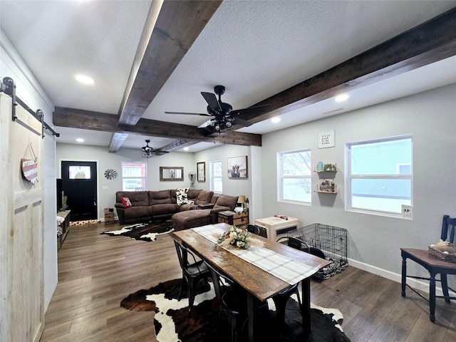 dining room featuring dark wood-style floors, a barn door, baseboards, and beamed ceiling